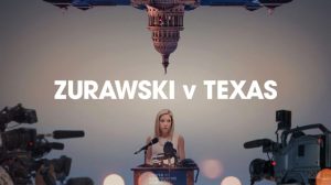 women speaking into a microphone in front of press, upside down capitol building directly on top of her